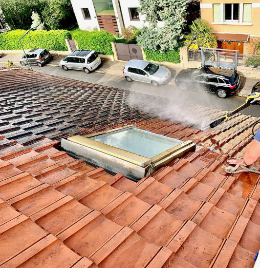 Démoussage d'une toiture en tuiles autour d'une fenêtre de toit