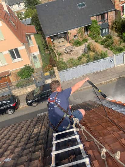 Artisan en train de nettoyer une toiture dans les Yvelines, les toits de France